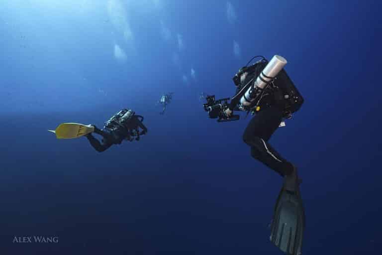 Rebreather divers swim in open blue water. Rebreather underwater filming